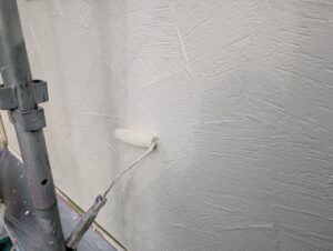 外壁上塗り作業の写真｜中間市N様邸の外壁塗装・22-85Cをローラーで均一に仕上げる工程